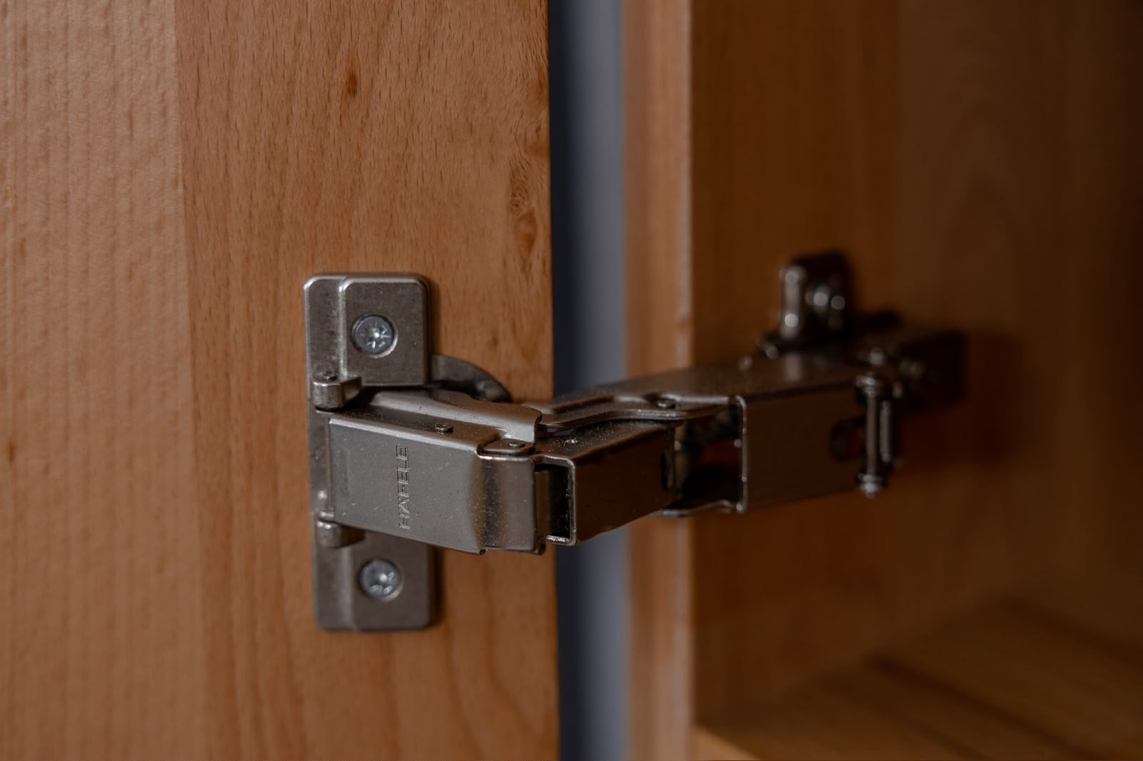 Close-up of cabinet hinge hardware on natural wood dormitory furniture