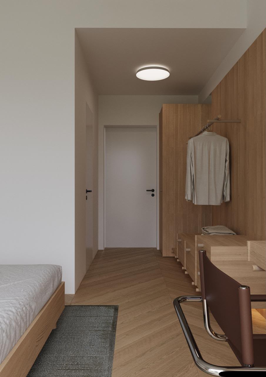 Light wood dormitory room with desk and storage along the hallway wall